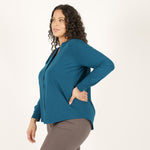 Woman wearing bright blue long sleeve button up shirt with brown fitted leggings